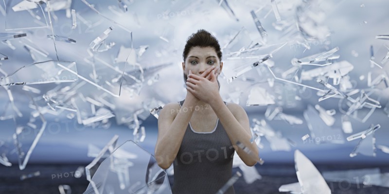 Shards of glass surrounding woman covering mouth with hands