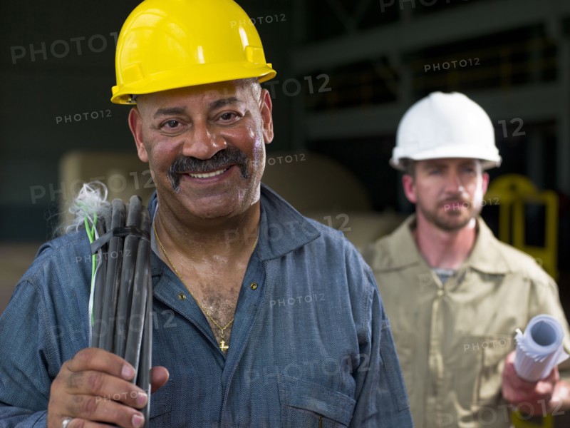 Construction workers holding blueprints and cable