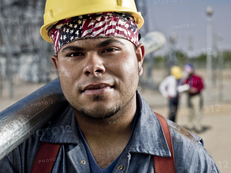 Mixed race construction worker carrying pipe