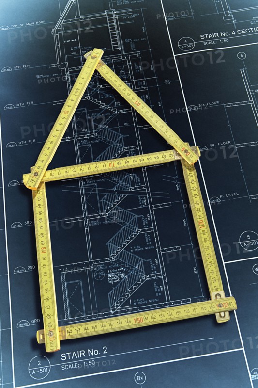 Rulers forming house over construction blueprints