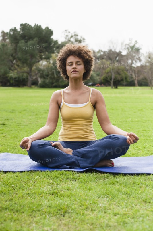 Mixed race woman practicing yoga in park