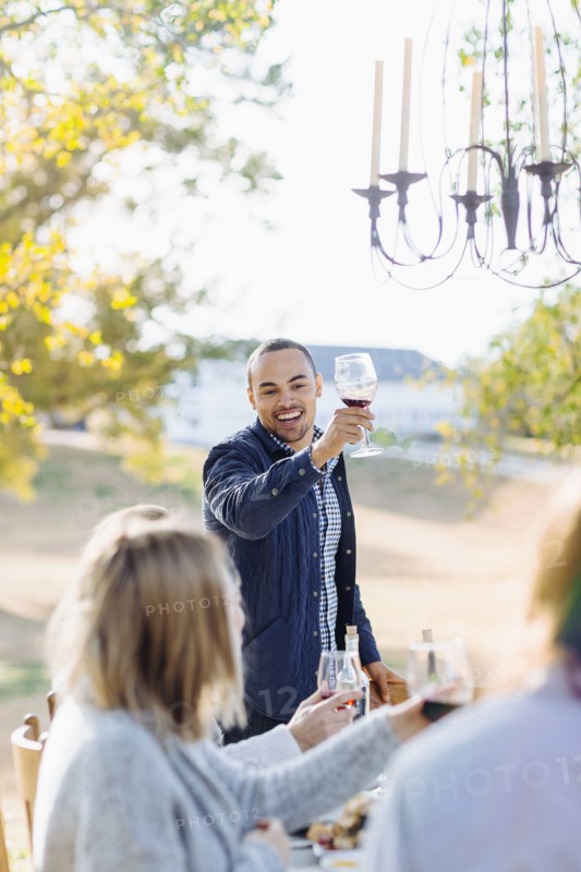 Friends toasting with wine at outdoor table
