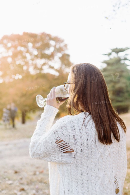 Caucasian woman drinking wine in rural field