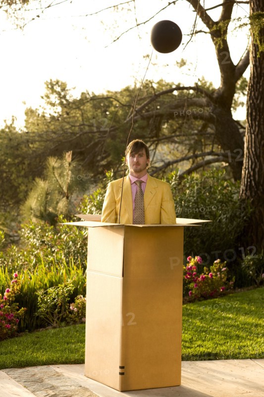 Caucasian man standing in large cardboard box outdoors