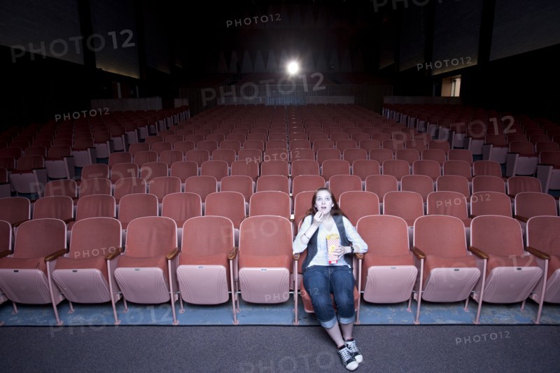 Caucasian woman watching move in empty theater