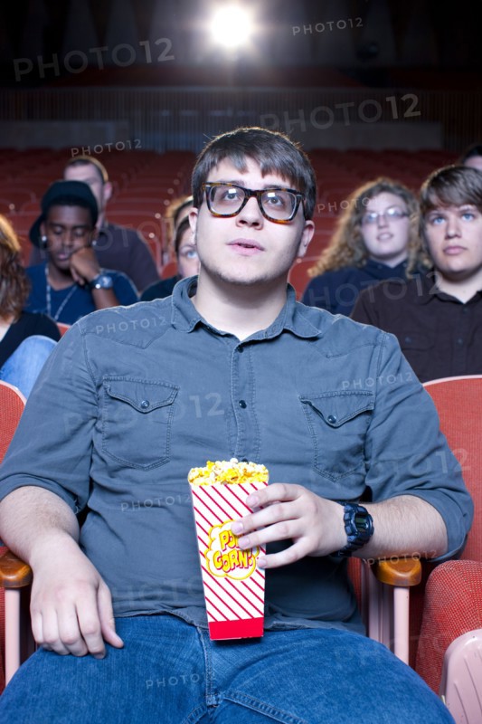 Caucasian man eating popcorn in movie theater