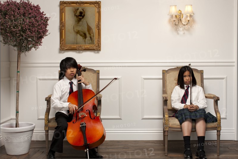 Vietnamese children with musical instruments sitting on elegant chairs