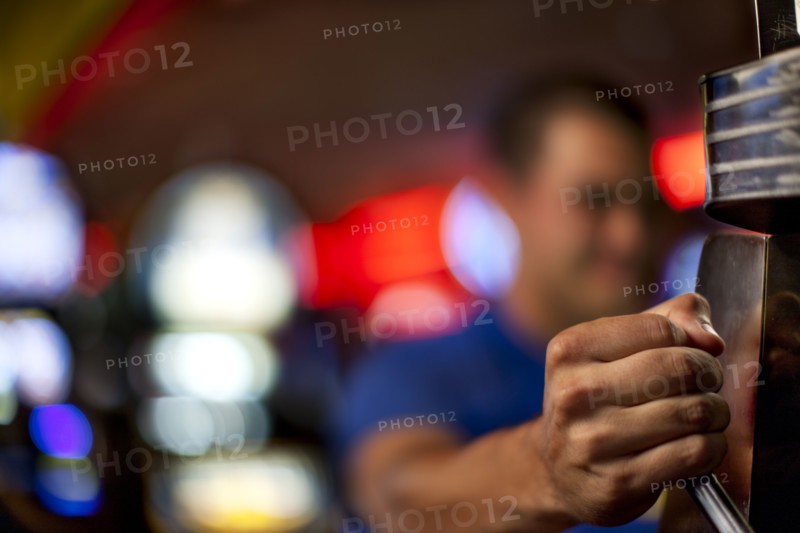 Native American man pulling lever of slot machine in casino