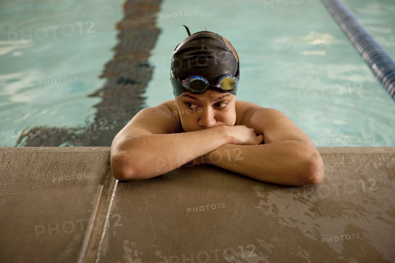 Unhappy Pacific Islander swimmer leaning at edge of pool