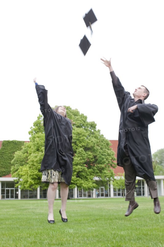Graduates throwing graduation caps into air