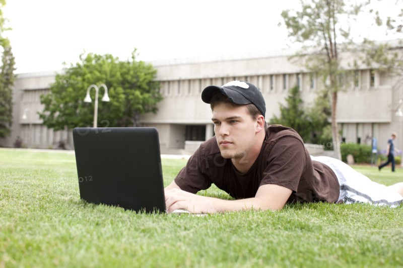 Serious Caucasian man using laptop in grass