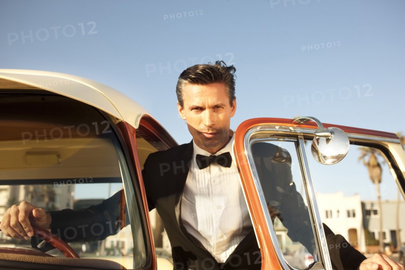 Caucasian man in tuxedo getting into car