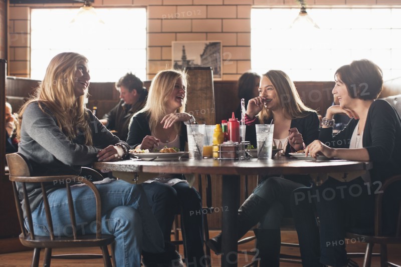 Caucasian teenagers eating together in restaurant