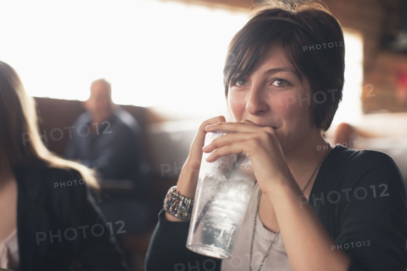 Caucasian teenager drinking water in restaurant