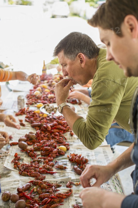 Caucasian men eating at crawfish boil