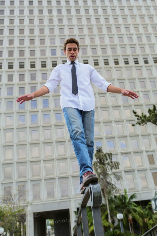 Hispanic businessman balancing on urban railing