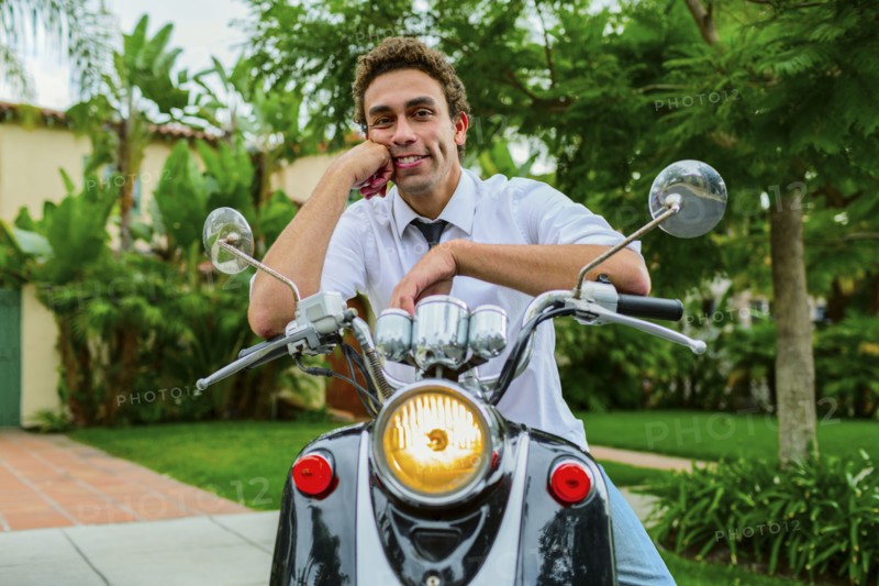 Hispanic businessman sitting on moped outdoors