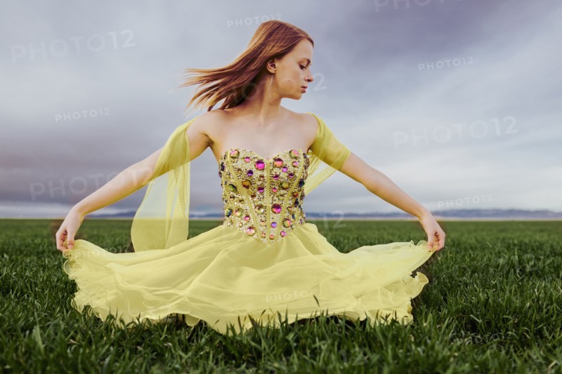 Caucasian teenage girl wearing gown in rural field