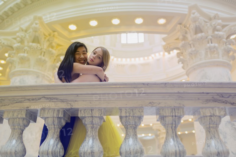 Teenage girls wearing gowns on ornate banister