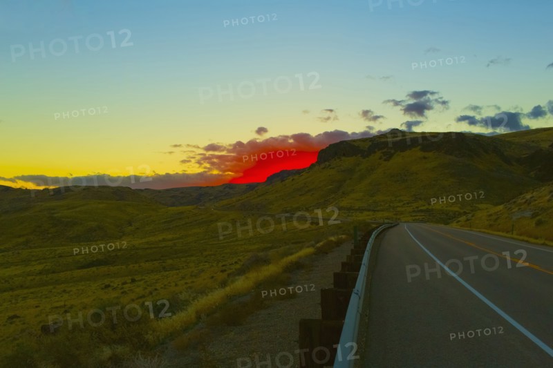 Red sunset over rural road and hillside