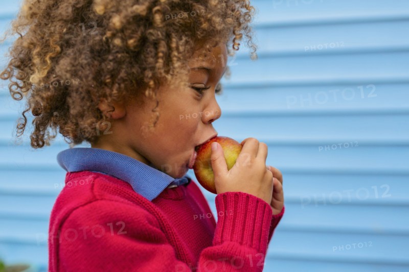 Pacific Islander boy eating apple outdoors