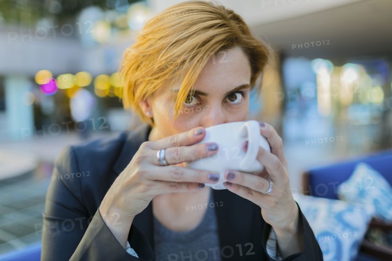 Caucasian businesswoman drinking coffee at sidewalk cafe