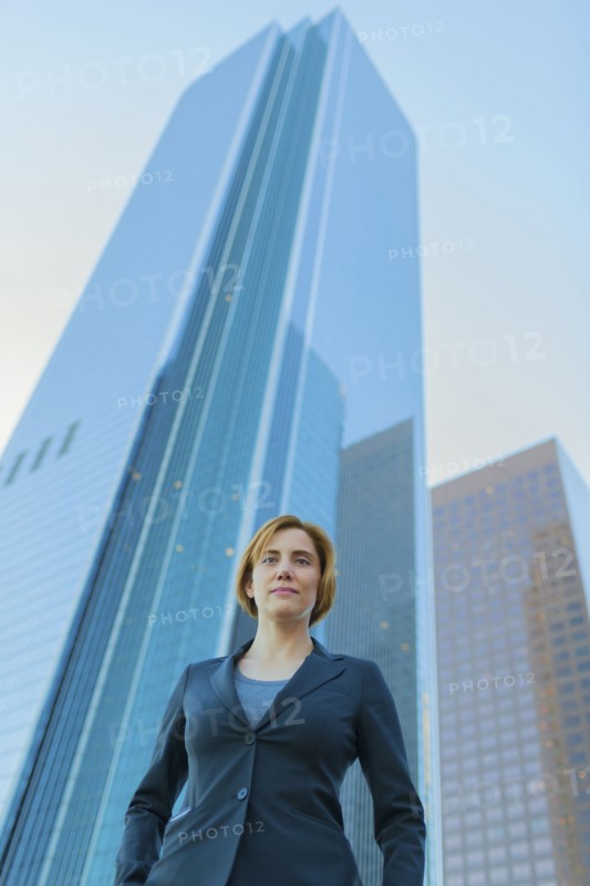 Low angle view of Caucasian businesswoman under high rise buildings