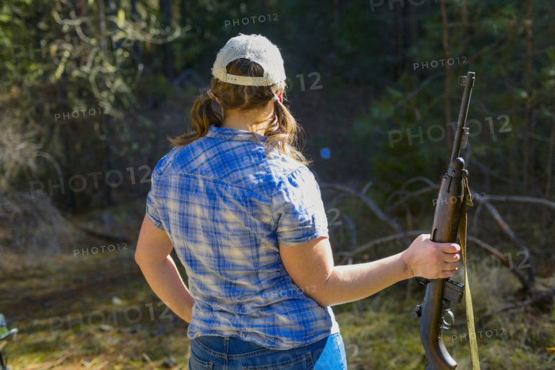 Caucasian woman carrying rifle in forest