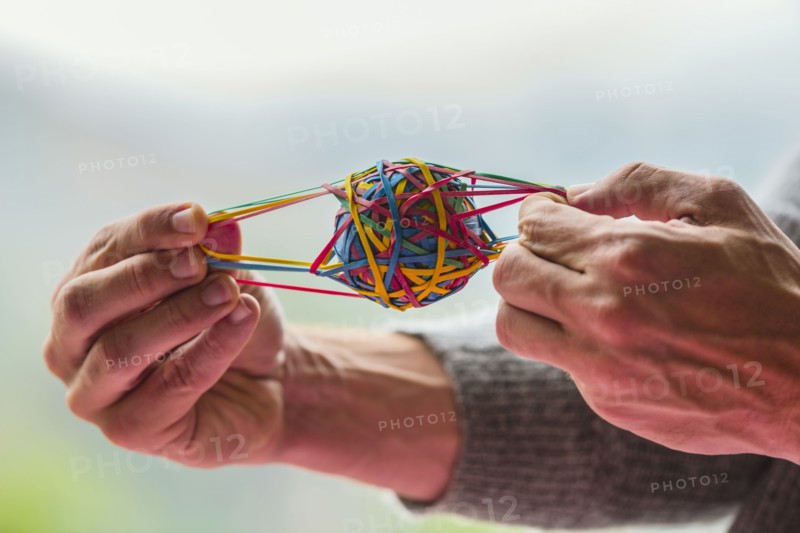 Close up of Caucasian man pulling rubber band ball