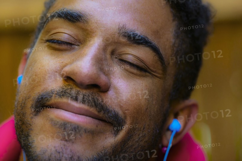 Close up of calm mixed race man listening to earbud