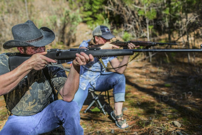 Caucasian hunters aiming guns in forest