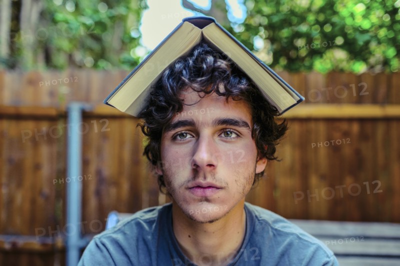 Hispanic man balancing book on head in backyard