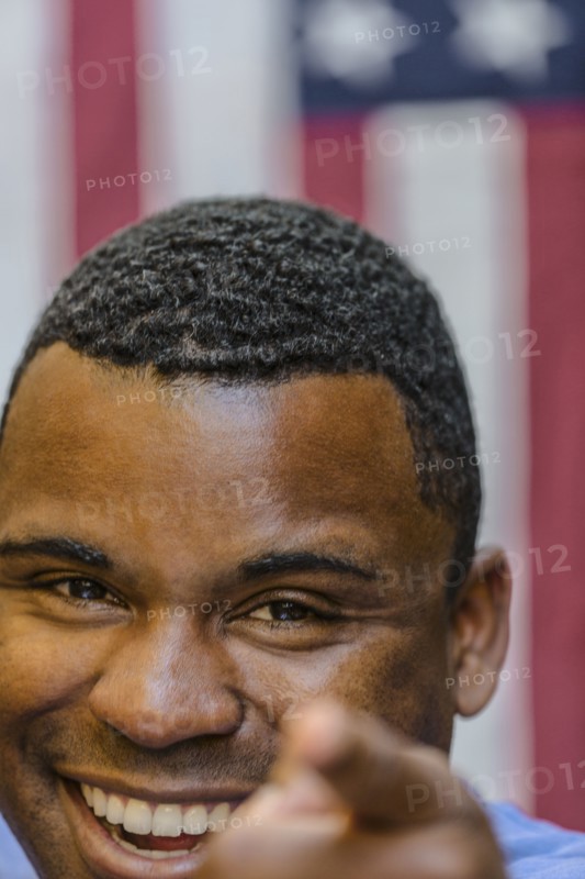 Close up of smiling Black man pointing in front of American flag