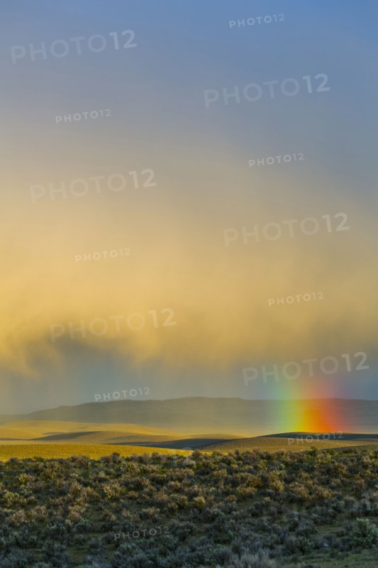 Rainbow and clouds over desert landscape