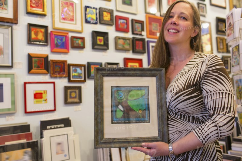 Caucasian artist holding artwork in gallery