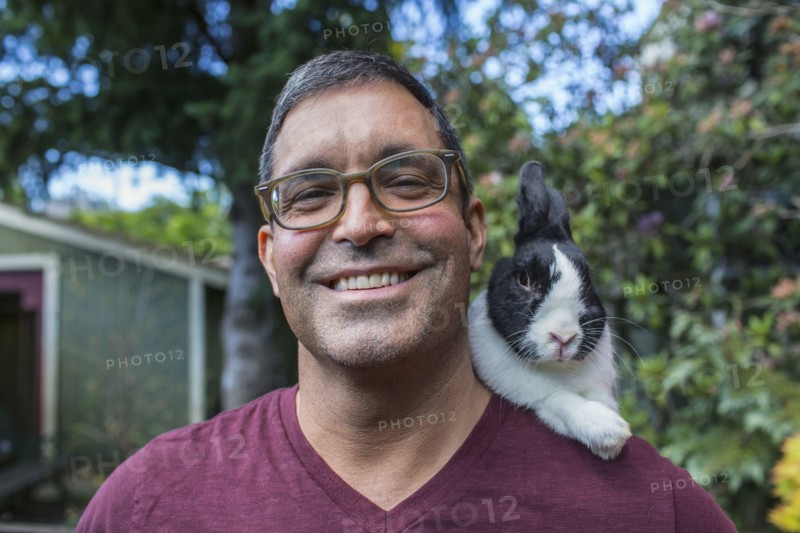 Mixed race man carrying rabbit on shoulder