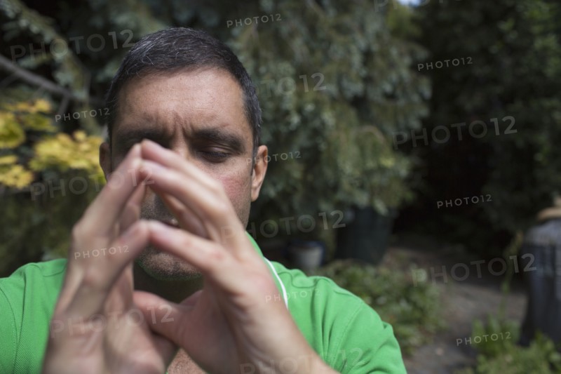 Mixed race man concentrating with hands clasped
