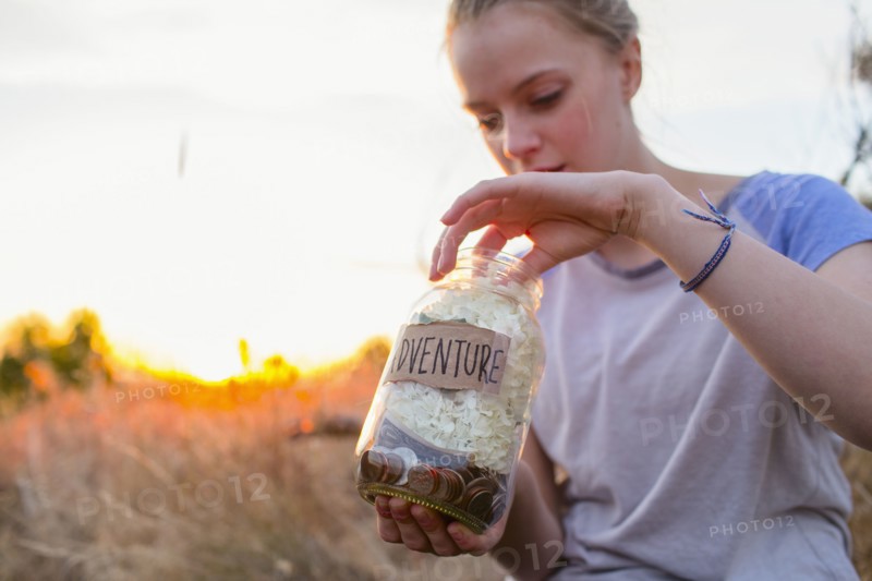 Caucasian teenage girl saving money in jar