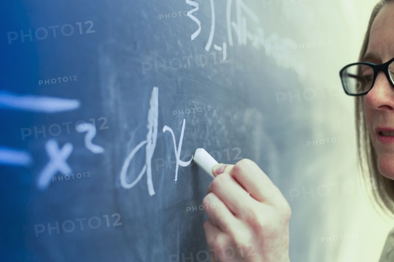 Caucasian teacher writing on chalkboard