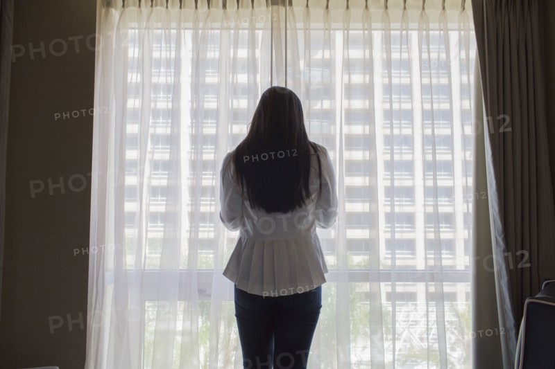 Asian teenage girl standing at hotel window