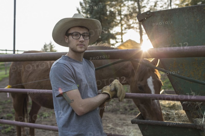 Caucasian farmer leaning on railing near horse