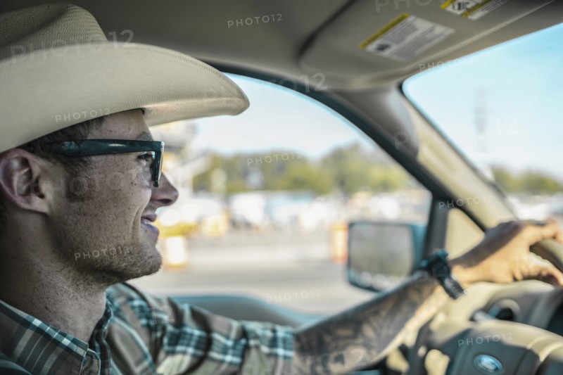 Caucasian man wearing cowboy hat driving car
