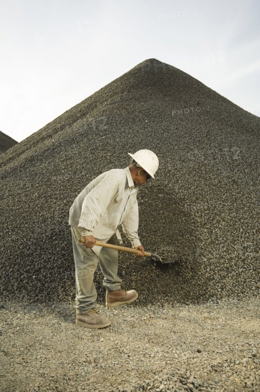 Hispanic man shoveling gravel
