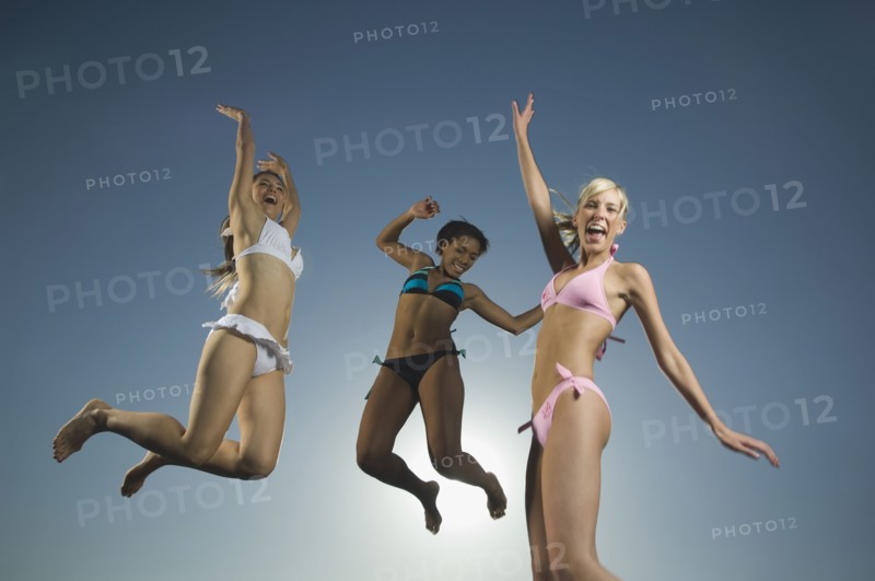 Multi-ethnic women in bathing suits jumping