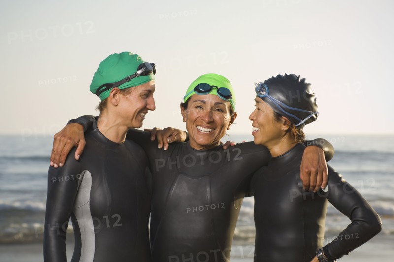 Multi-ethnic women wearing wetsuits and goggles