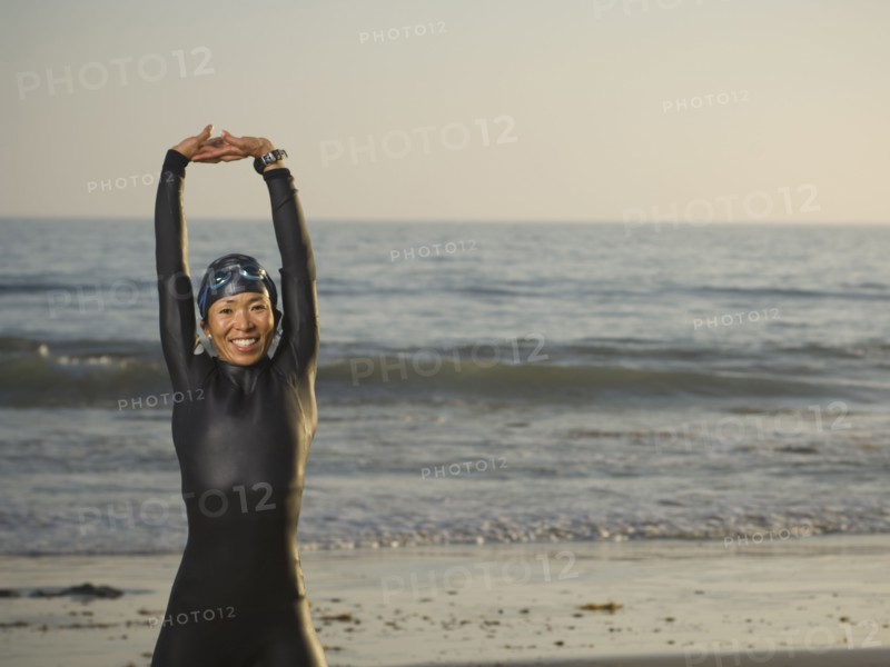 Asian woman stretching in wetsuit and goggles