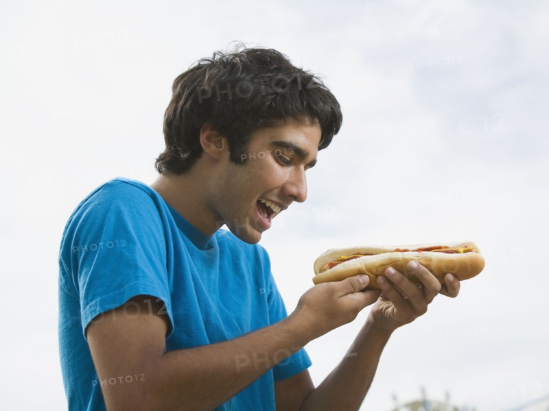 Mixed Race teenaged boy eating hot dog