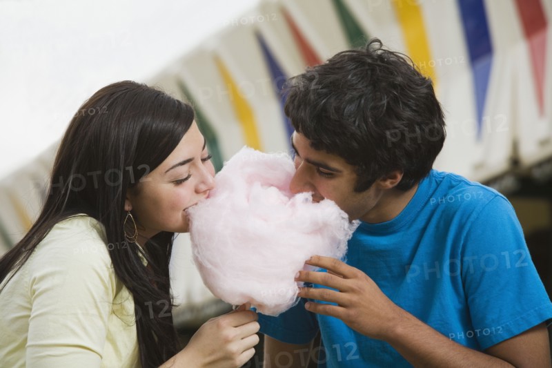 Multi-ethnic teenaged couple eating cotton candy