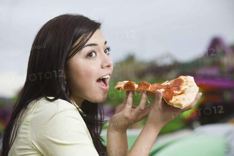 Mixed Race teenaged girl eating pizza
