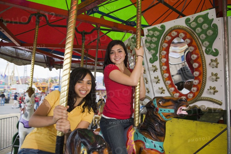 Mixed Race teenaged girls on carousel horse
